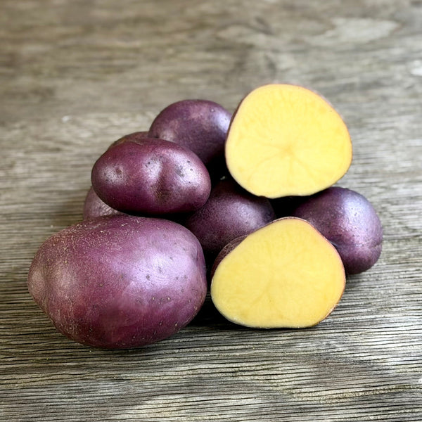Purple and yellow potatoes on a wooden surface