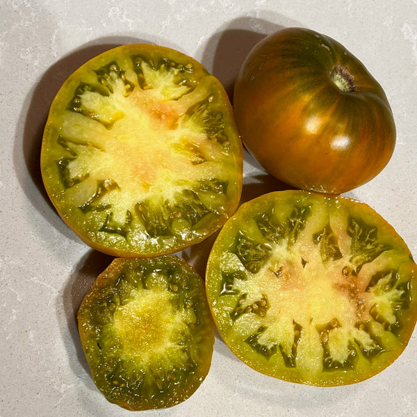 Sliced kiwi mango tomatoes on a gray surface with a blue label.